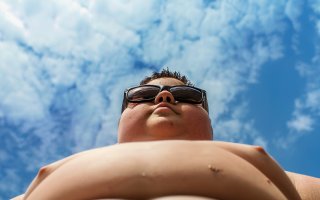 low-angle photo from below, of a chubby boy wearing sunglasses